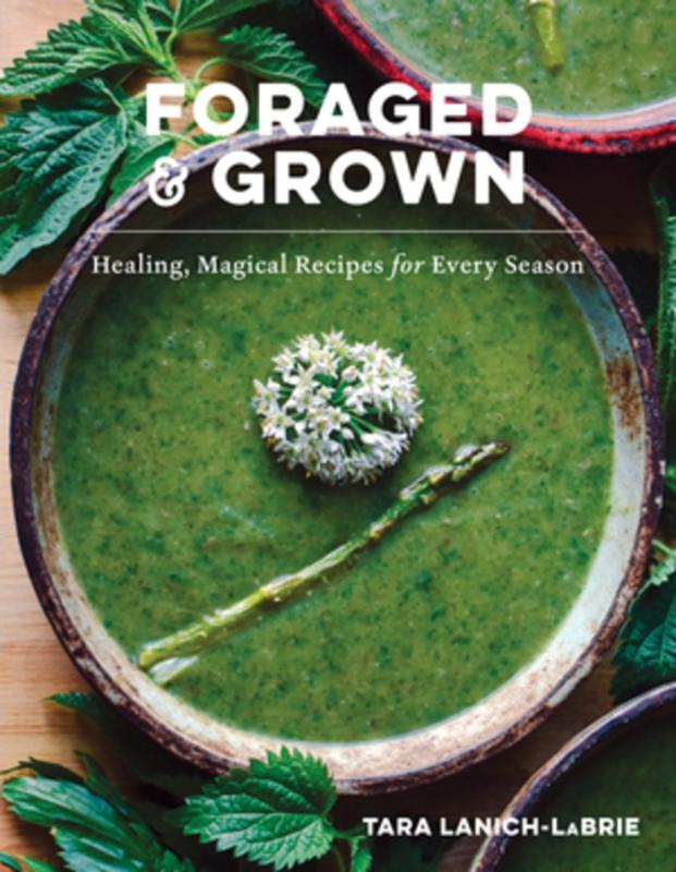 Green soup with herbs around the bowl, with a sprig of asparagus and flowers in the center