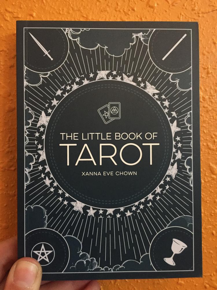 Navy blue cover with white detailing and the four signs of the tarot