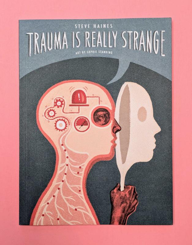 Cover of Trauma is Really Strange which features a human bust in profile holding up a mask over its face. Inside the head, there are gears and alarms. 