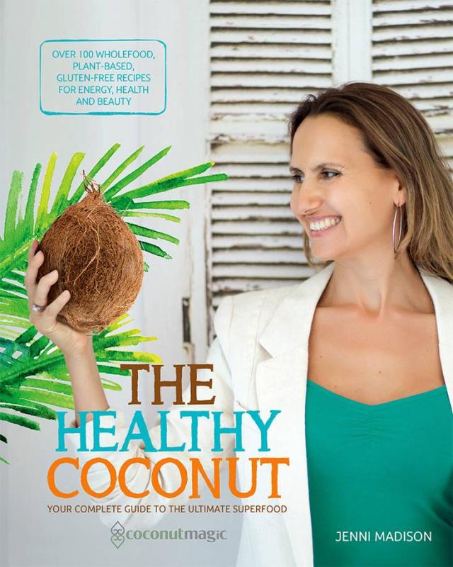 Person in a lab coat holds a coconut, standing next to a plant, in front of some white shutters