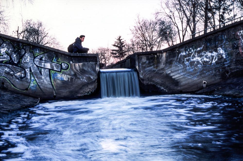 a young person sits at the edge of an industrial waterfall