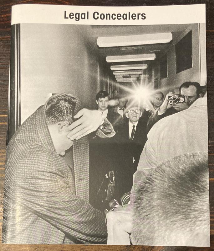 a photograph of a man covering his face and a hallway full of photographers trying to take his picture