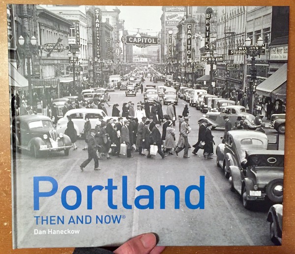 a vintage black and white photo of a street with old cars and people milling around