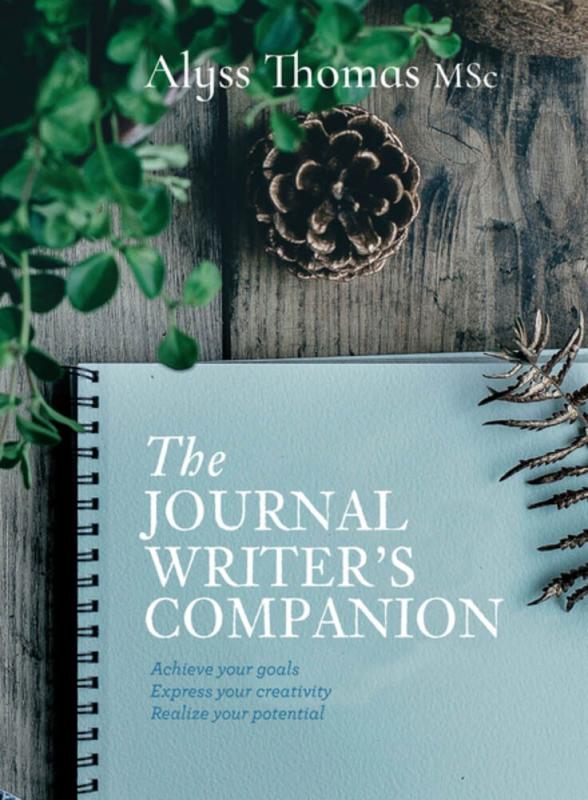 The journal rests on a picnic table next to a pinecone and some bushes.