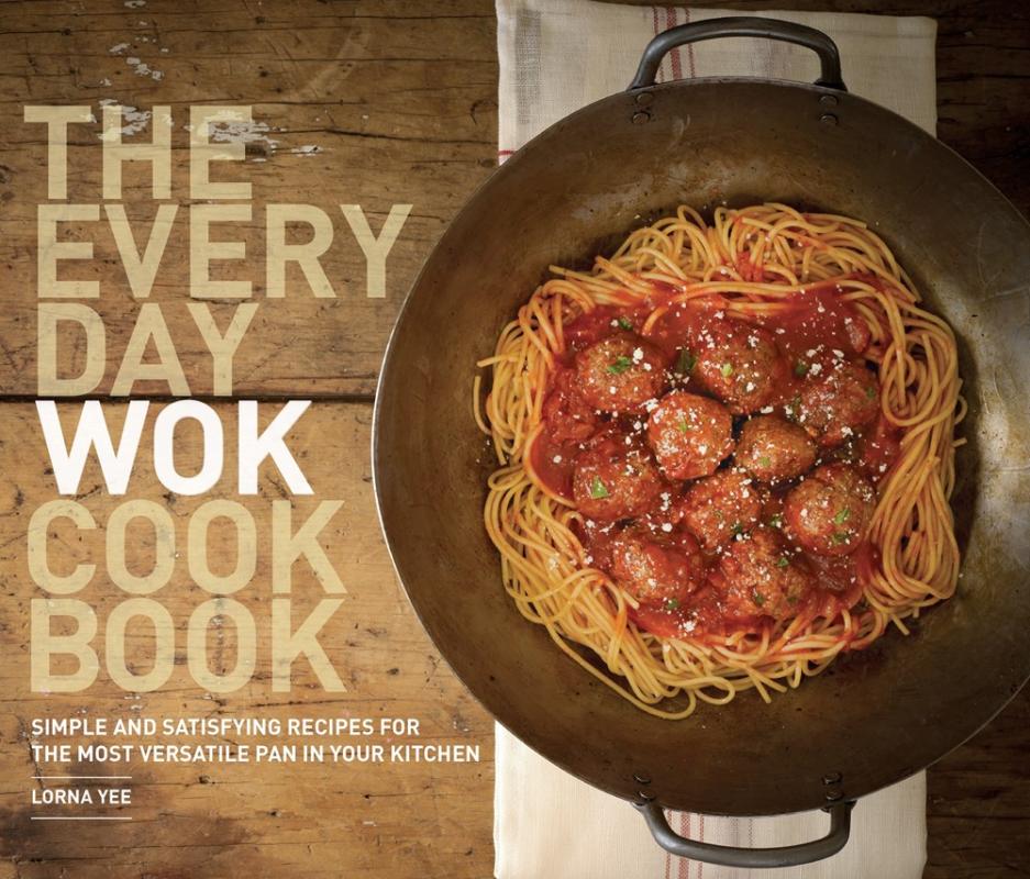 offset image of a wok with spaghetti and meatballs on a wooden counter